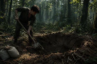 a man is digging a hole in the forest